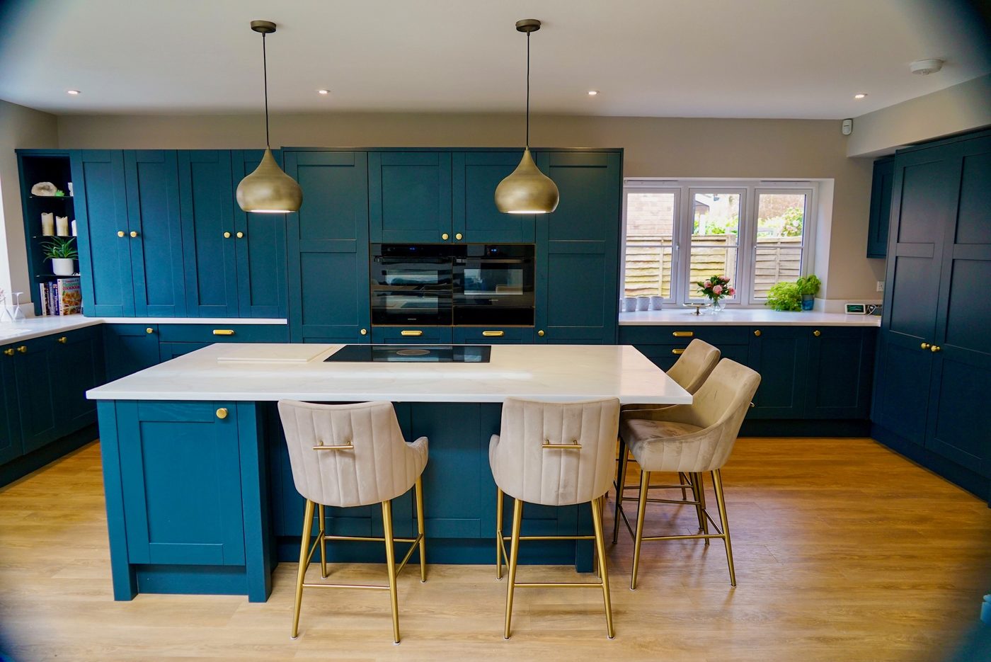 Blue kitchen with integrated ovens and a stone-topped island