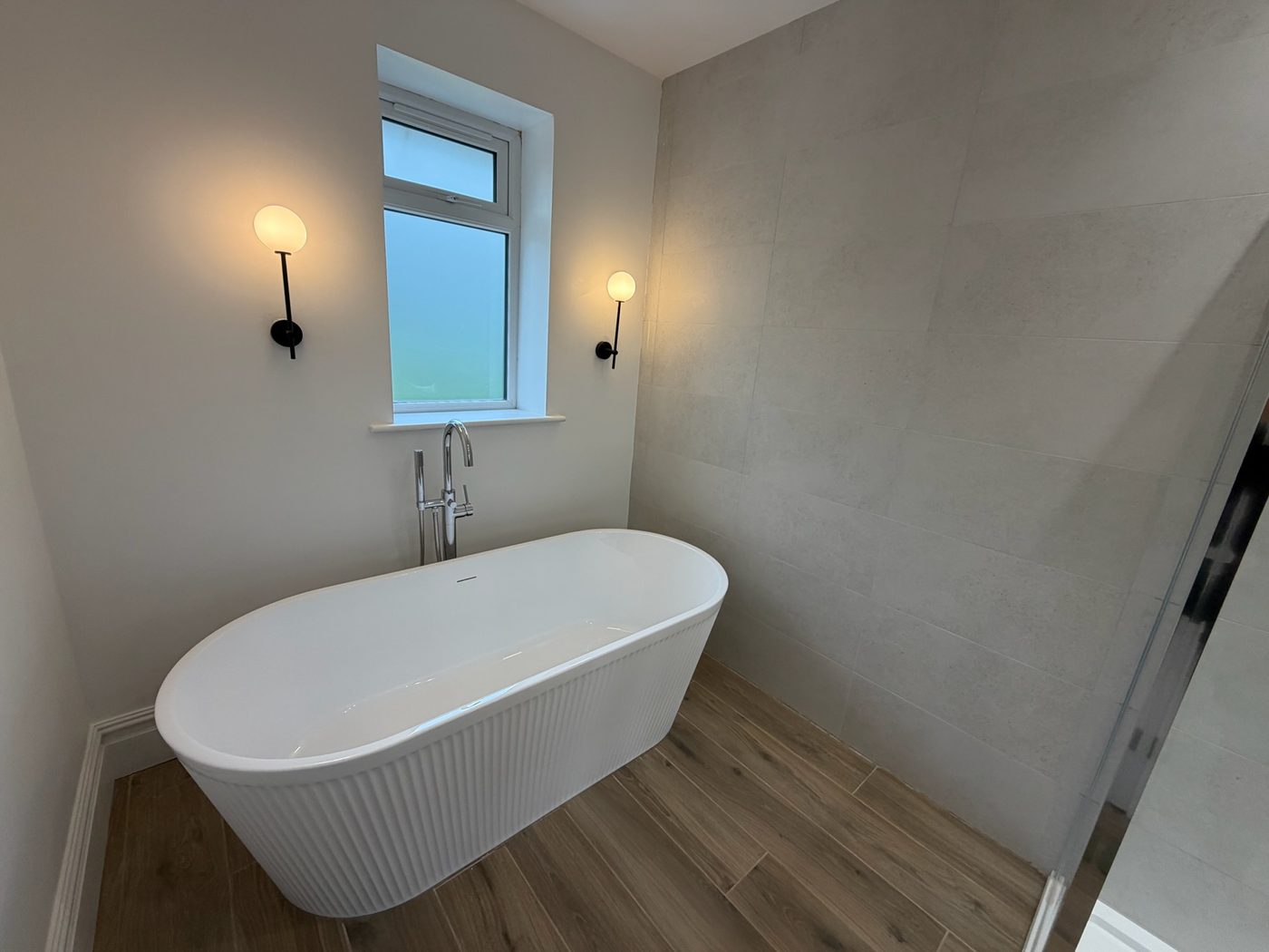 Freestanding fluted bath beneath a window in a new bathroom