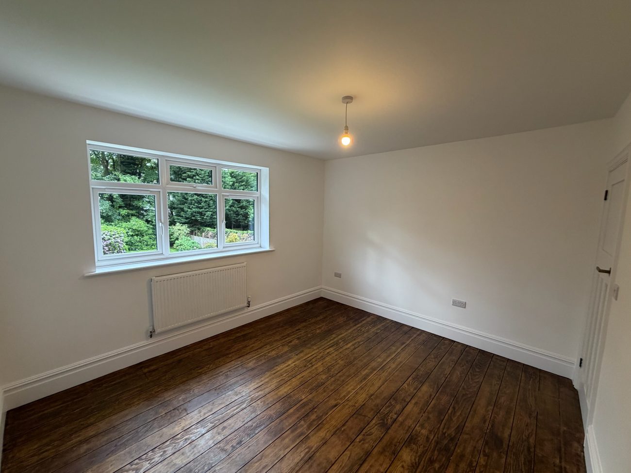 Bedroom with restored timber flooring and a garden outlook